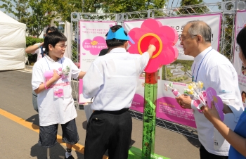전곡항 경기국제보트쇼장을 방문한 한 관람객이 강지원 변호사와 김세진 군의 안내를 받으려 푸르메재활전문병원 건립을 위해 천원 기부하고 있다.