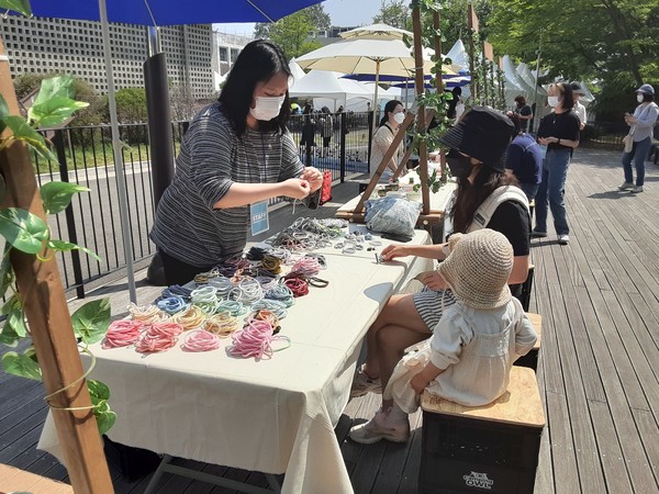 아이와 함께 행사장을 찾은 참관객이 양말끈을 활용한 팔찌의 제작 방식에 대해 설명을 듣고 있다. /사진=최용구 기자