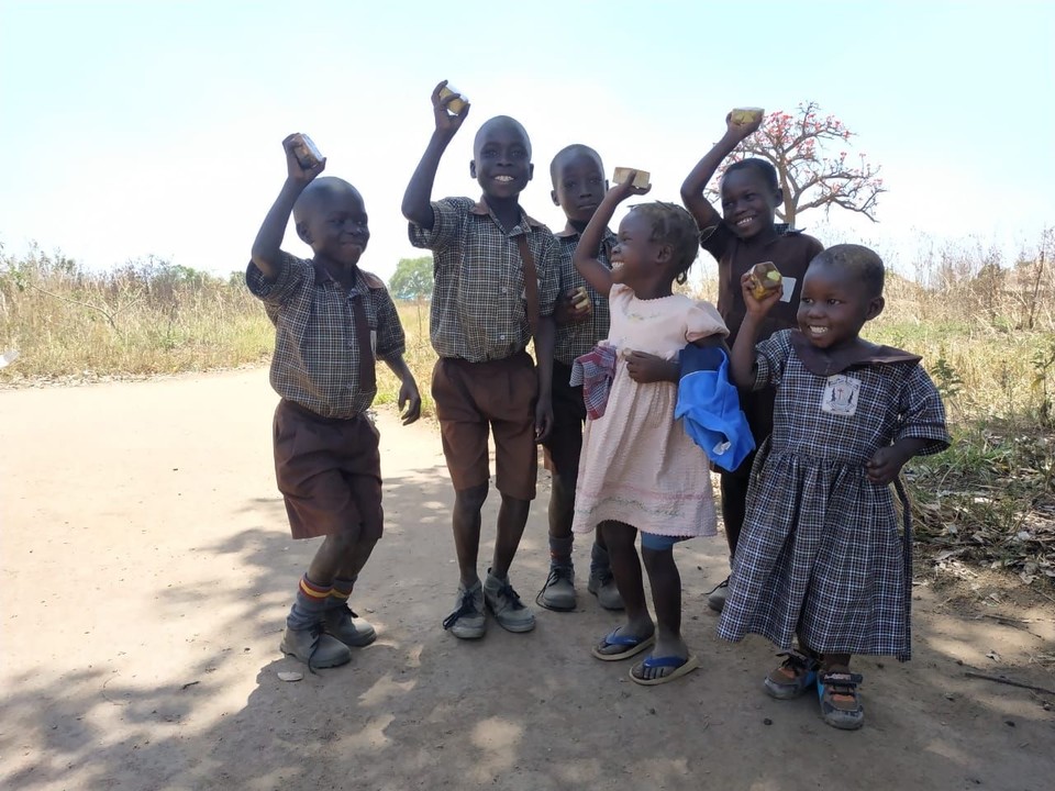 옮김의 비누를 들고 환하게 웃고 있는 우간다 아무루 지역 아이들
