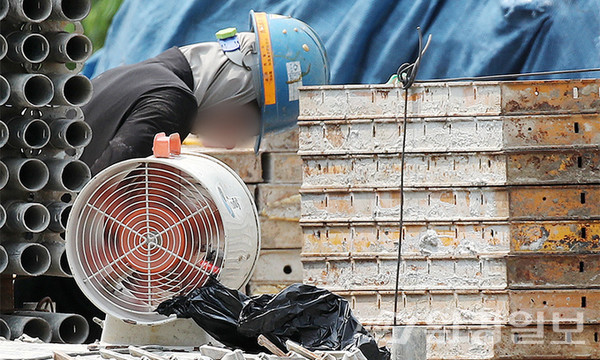 올해 역대급 폭염에 한 노동자가 건설공사장에서 더위에 지쳐 작은 선풍기 앞에서 한숨 돌리고 있다. 