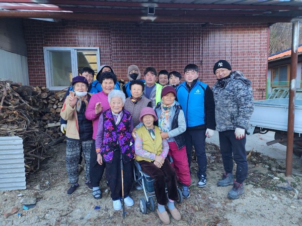 울진읍 사랑의 땔감 나누기 행사 참여자들이 이웃들과 기념촬영을 하고 있다. /사진제공=남우진 기자