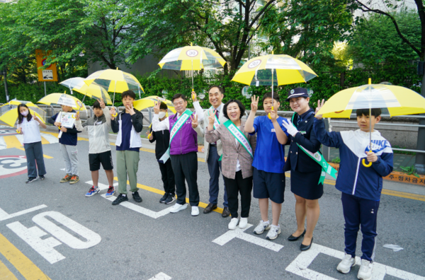 교통안전 캠페인 참여자들과 학생들이 안전우산을 들고 기념촬영을 하고 있다. /사진제공=동대문구