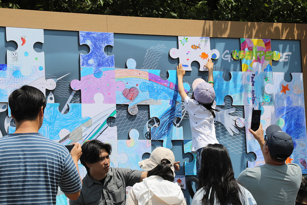 행사에 참가한 어린이가 깨끗하고 건강한 바다 그림을 퍼즐 조각에 그리고 있다.