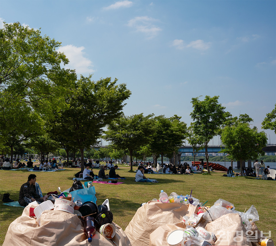 여의도 한강공원에서 한가로이 즐기는 시민들 옆에 수거된 재활용 쓰레기가 놓여 있다. /사진=노선민