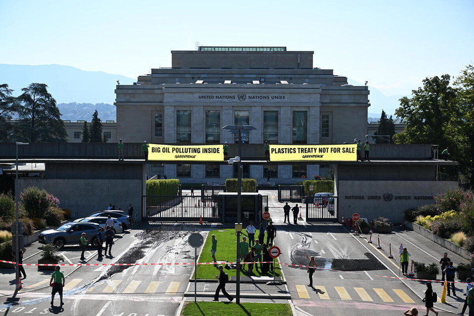 국제환경단체 그린피스 활동가들이 지난 7일 스위스 제네바에 위치한 유엔본부 입구에 석유화학 업계를 상징하는 검은 기름 자국을 남기고, 유엔본부 출입문 난간에 올라 ‘거대 석유화학 업계가 협상장을 오염시키고 있다’, ‘국제 플라스틱 협약은 거래 대상이 아니다'라고 쓰인 현수막을 펼치는 시위를 펼치고 있다. /사진제공=그린피스