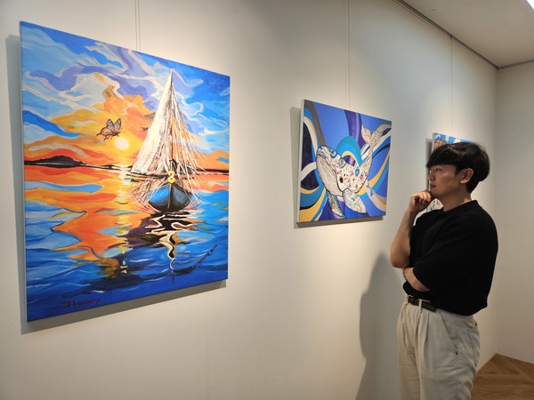 현대제철 직원이 ㈜올모용인 사업장에 걸린 소속 발달장애인 작가들의 작품을 감상하고 있다. /사진제공=현대제철